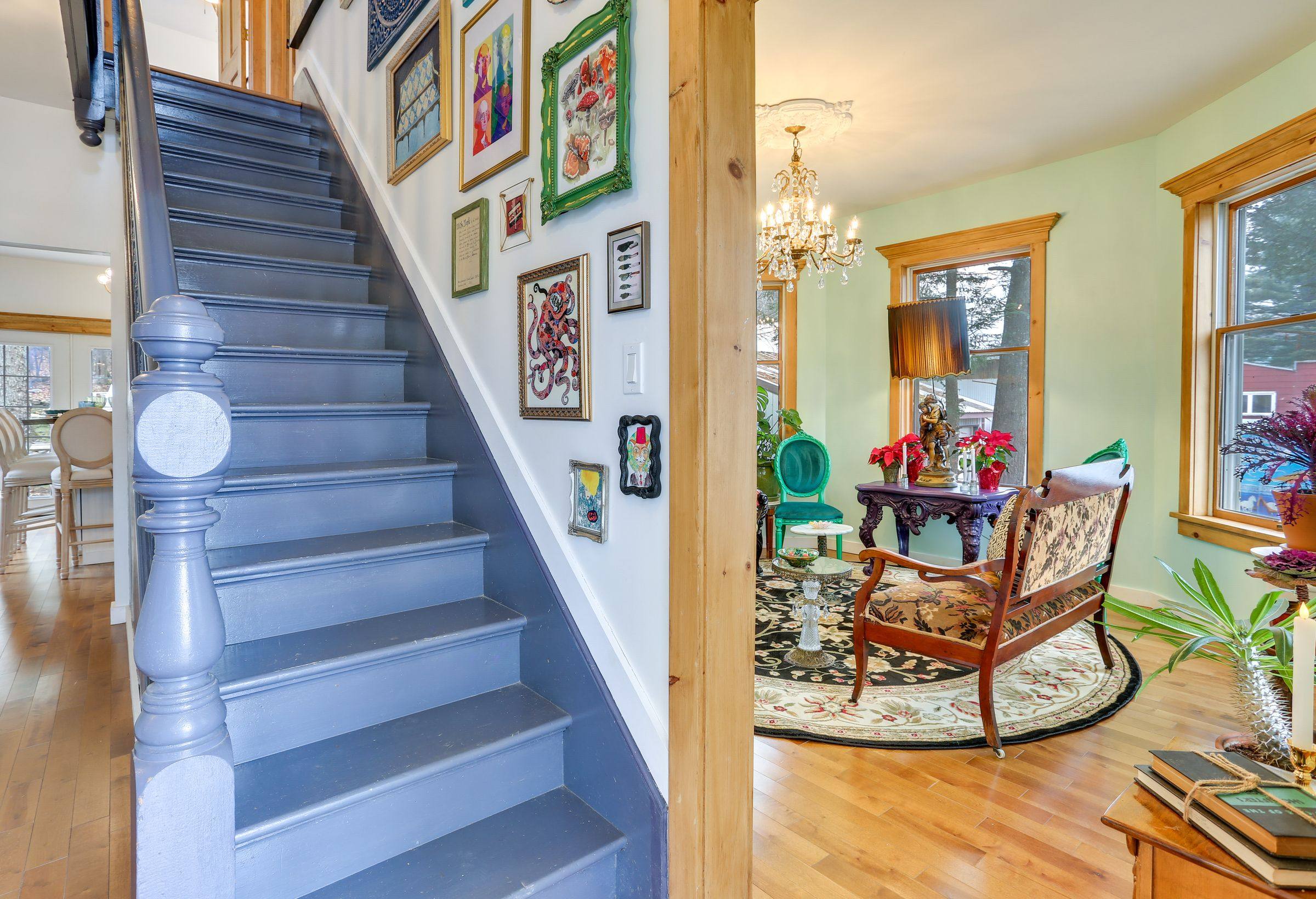 The original staircase, painted slate blue, rising past a salon-style wall of framed art.