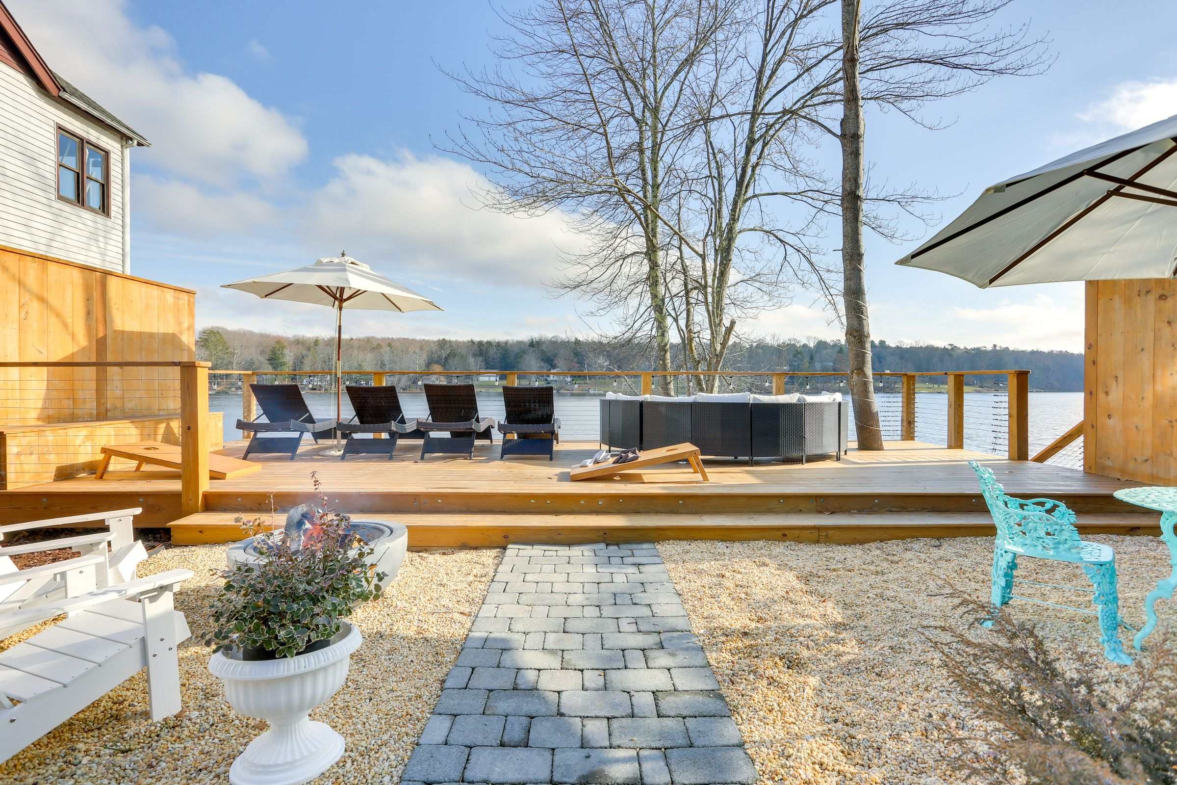 The multi-tier lakefront deck with loungers, umbrellas and the hot tub set directly above Lake Huntington.
