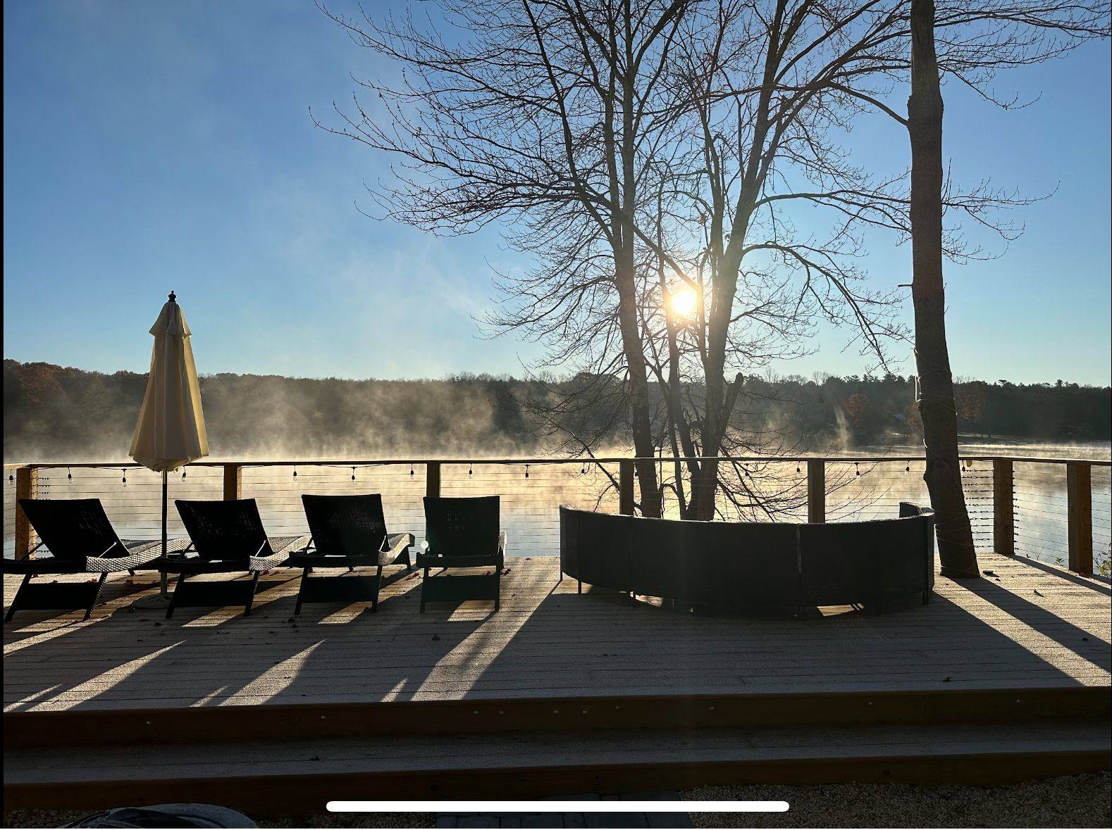 Sunrise mist rising off Lake Huntington in front of the empty lounge chairs on the deck.