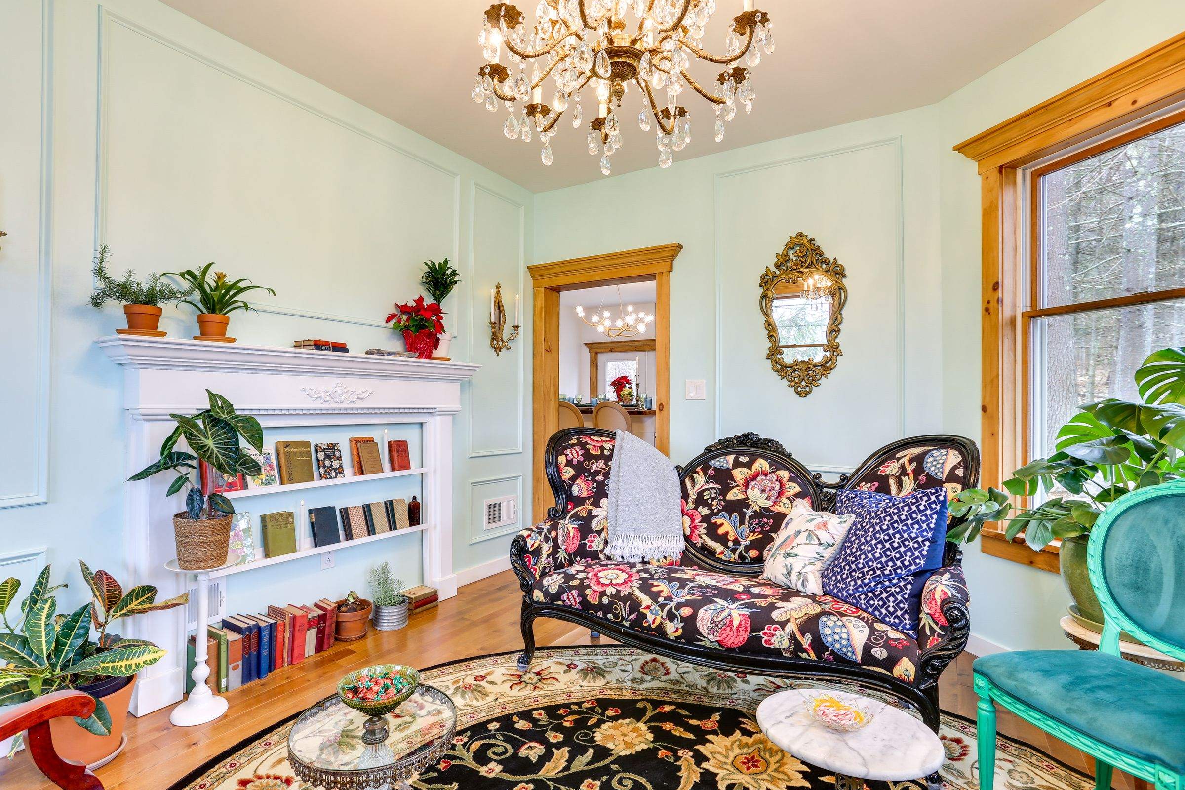 The literary salon: a white mantel lined with books and plants beside a Victorian settee.